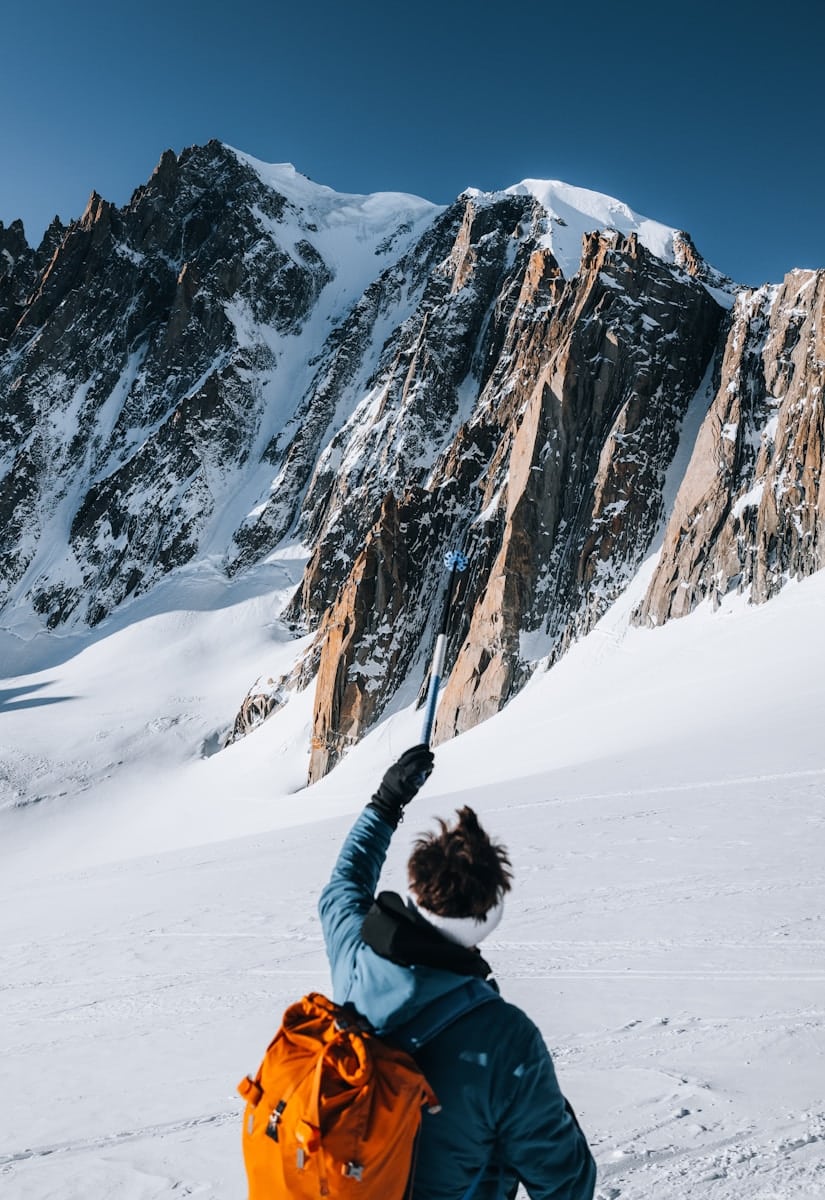 A person standing on a snow covered mountain with their arms in the air